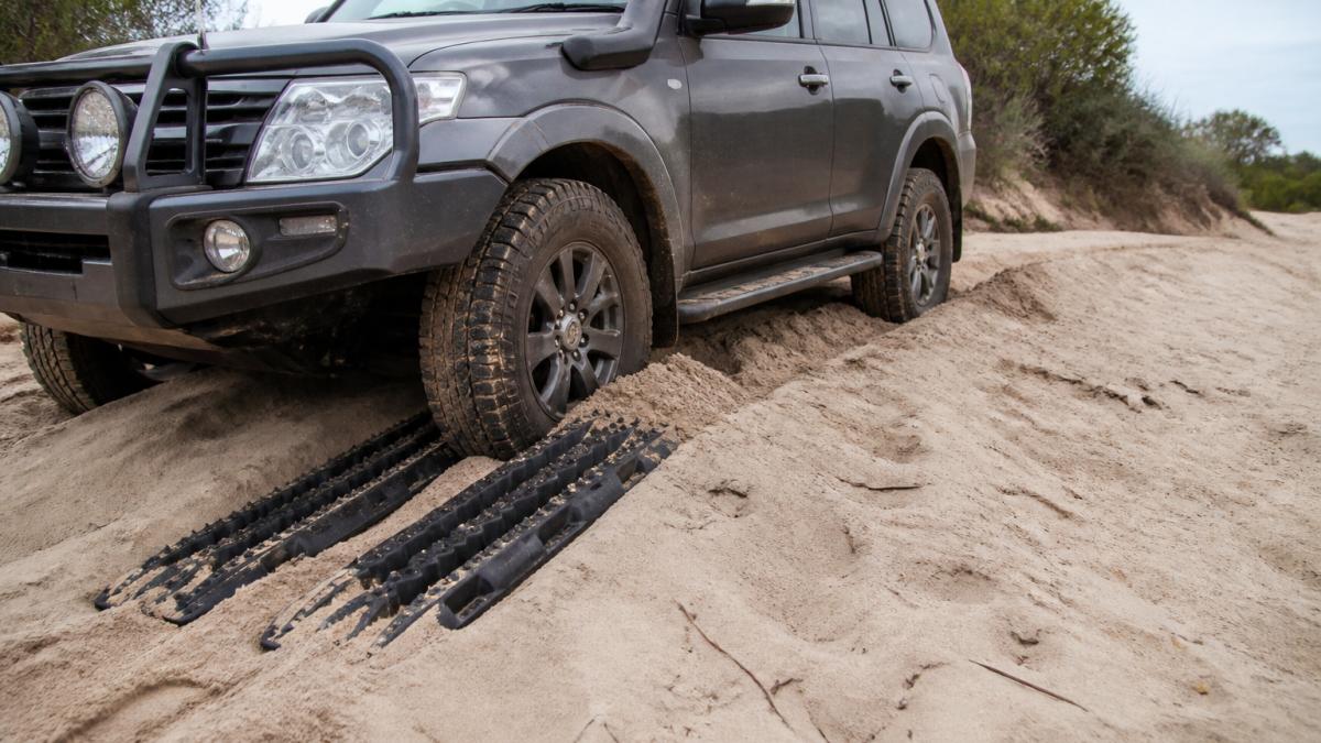 Diagram showing how to use recovery boards in sand by wedging them at a 30-degree angle under the vehicle's tyres.